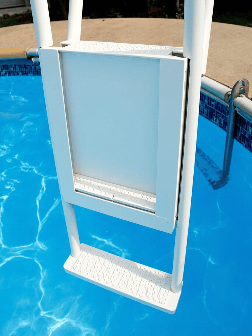 White A-frame safety pool ladder with closed swing-up barrier gate panel on top, hooked over an above-ground pool wall